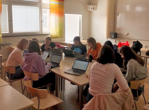 en grupp elever som sitter i ring framför sina laptops